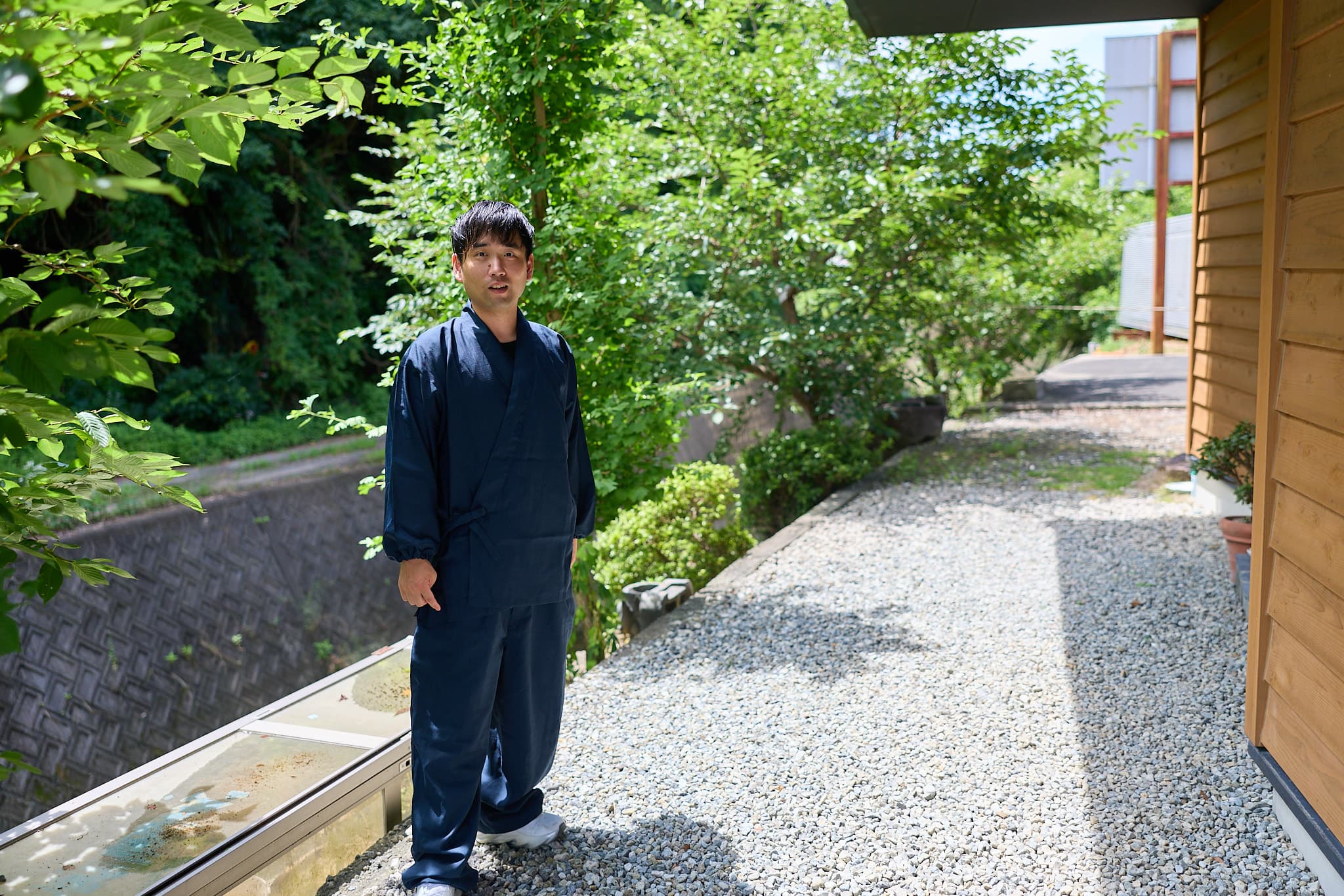 日本家屋の庭先に立つ、作務衣姿の森下友喜