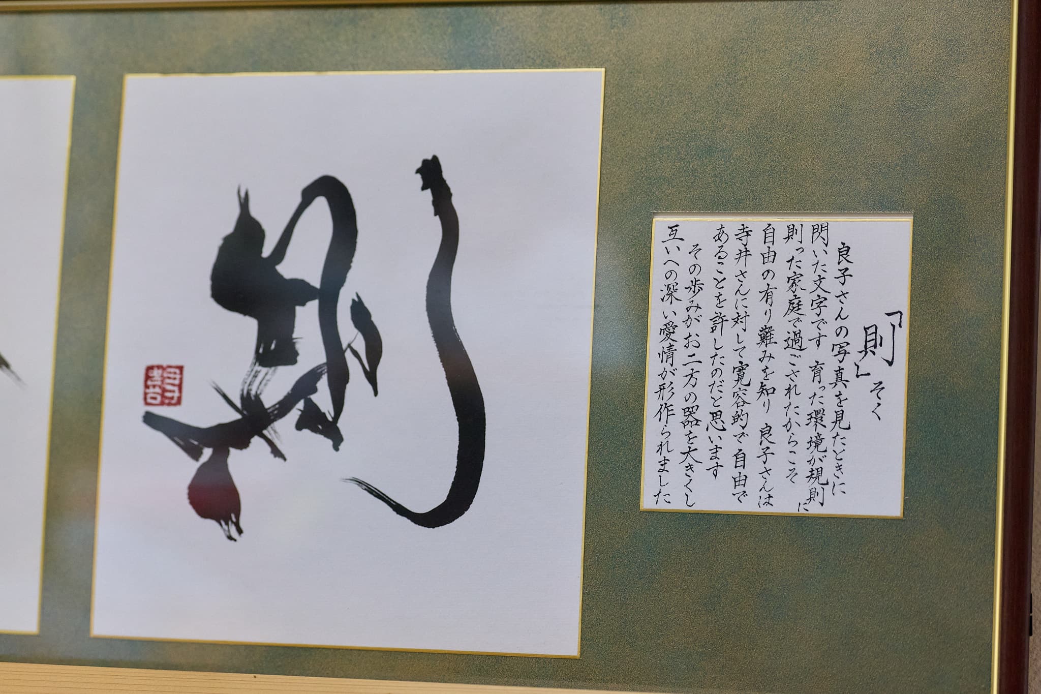 額装作品「則（そく）」と解説書き。亡き奥様・良子さんへ捧げた一文字