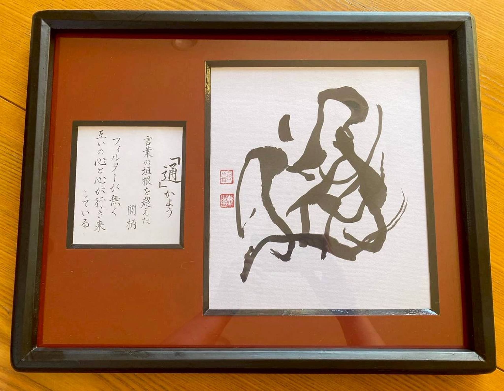 黒漆塗りの額に収めた抽象的な墨書「通」と解説詞