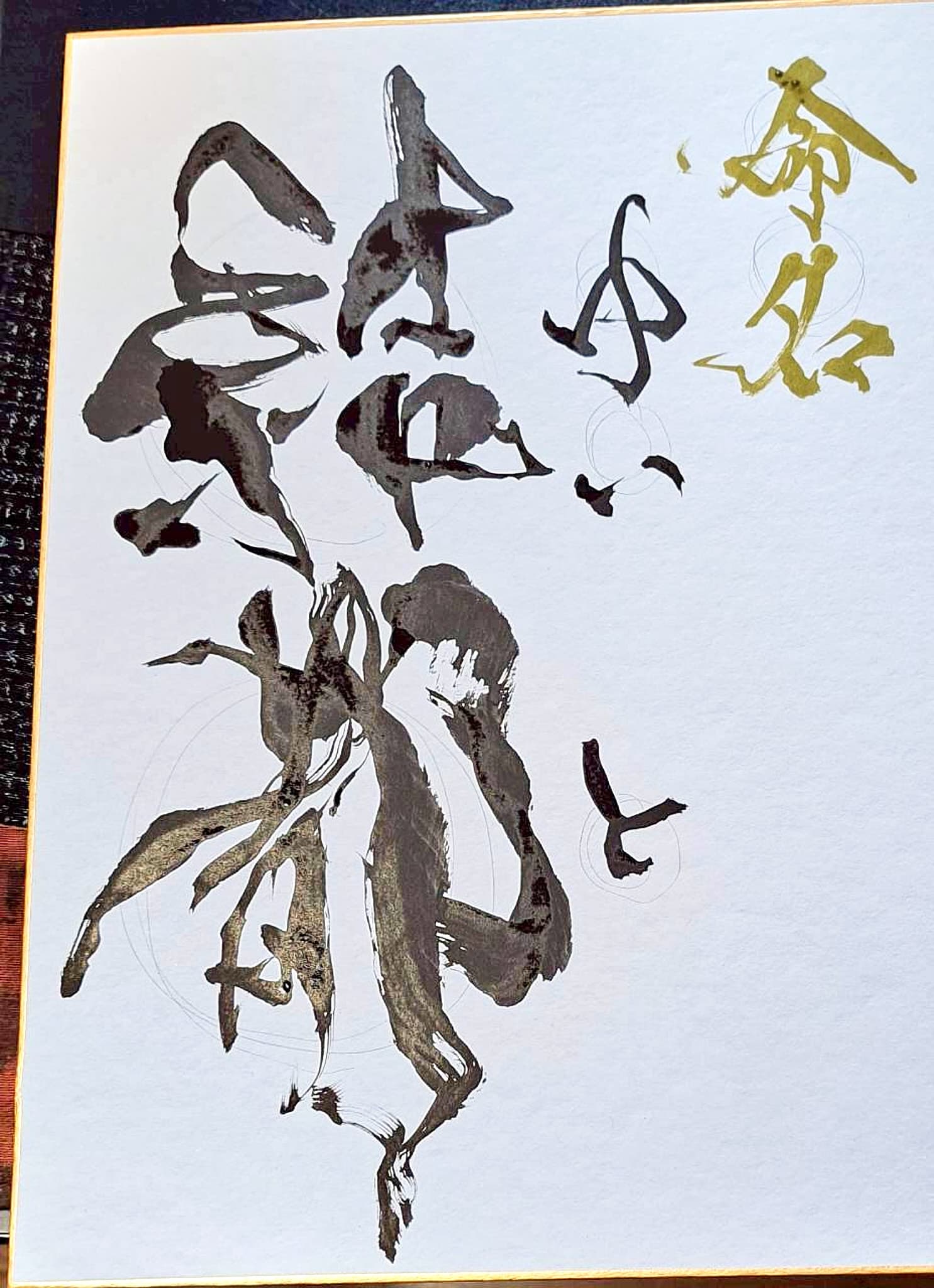 金縁の大色紙に草書で書かれた命名書、黄色の「命名」の文字