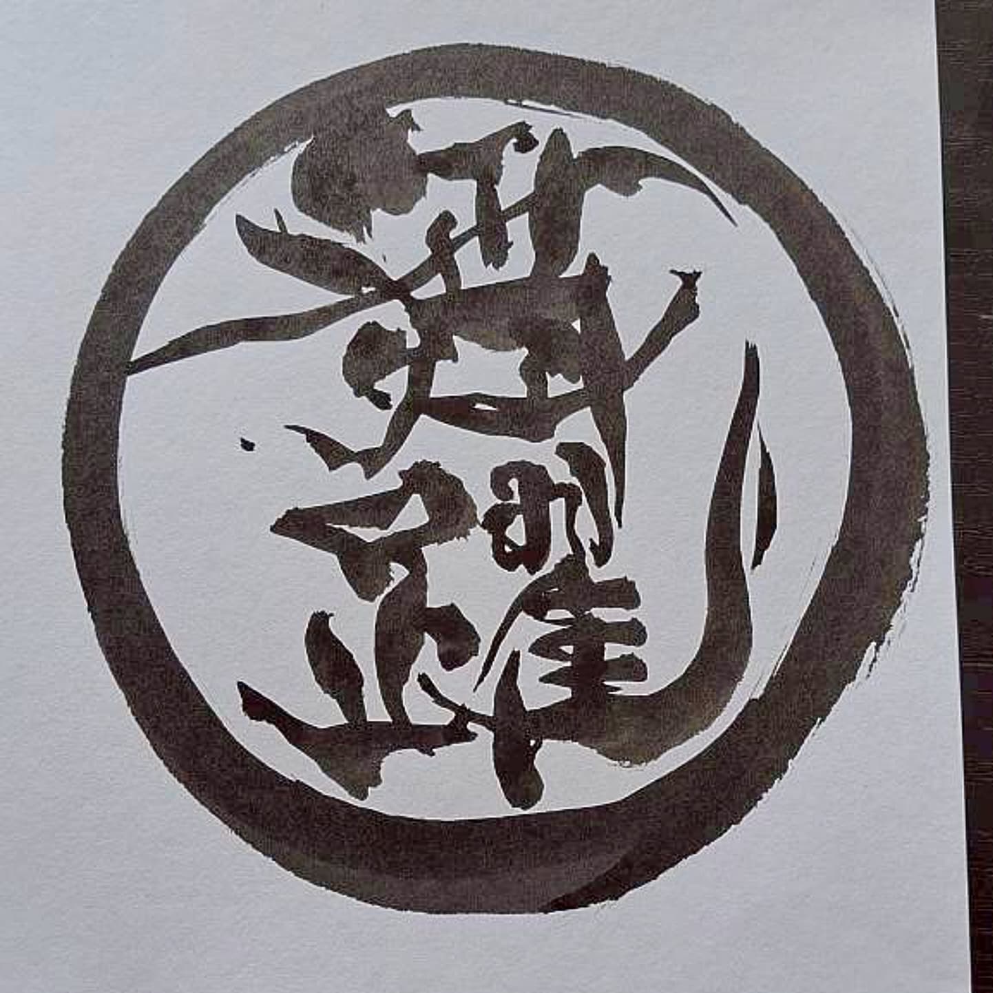 墨の円相の中に漢字を組み合わせた印章風のロゴ