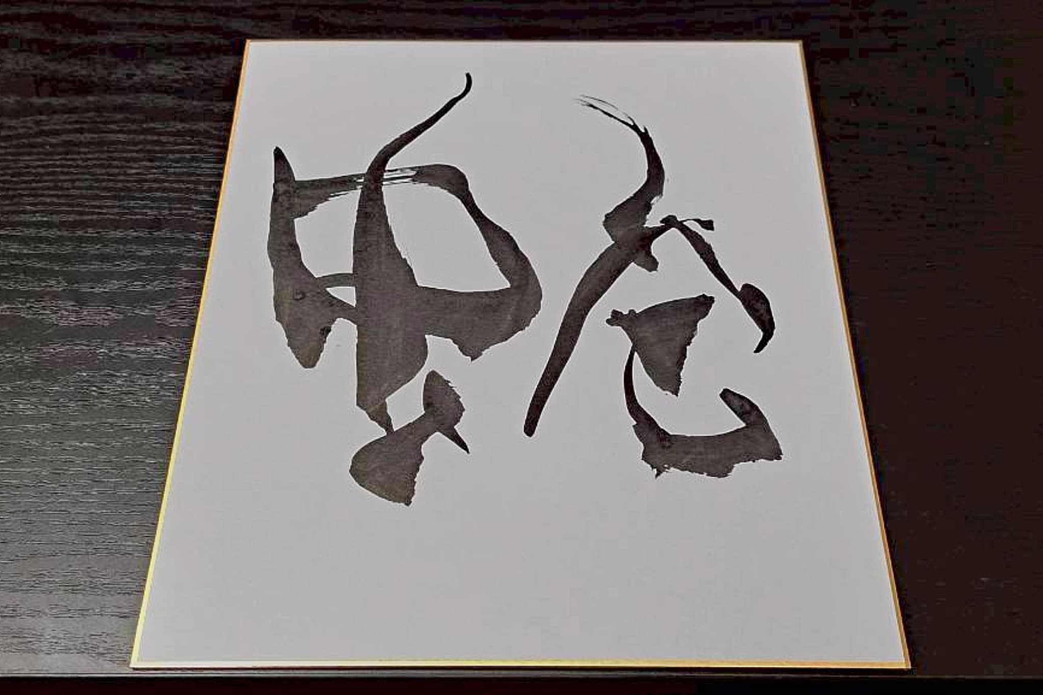 金縁の色紙に墨で記した一字「蛇」