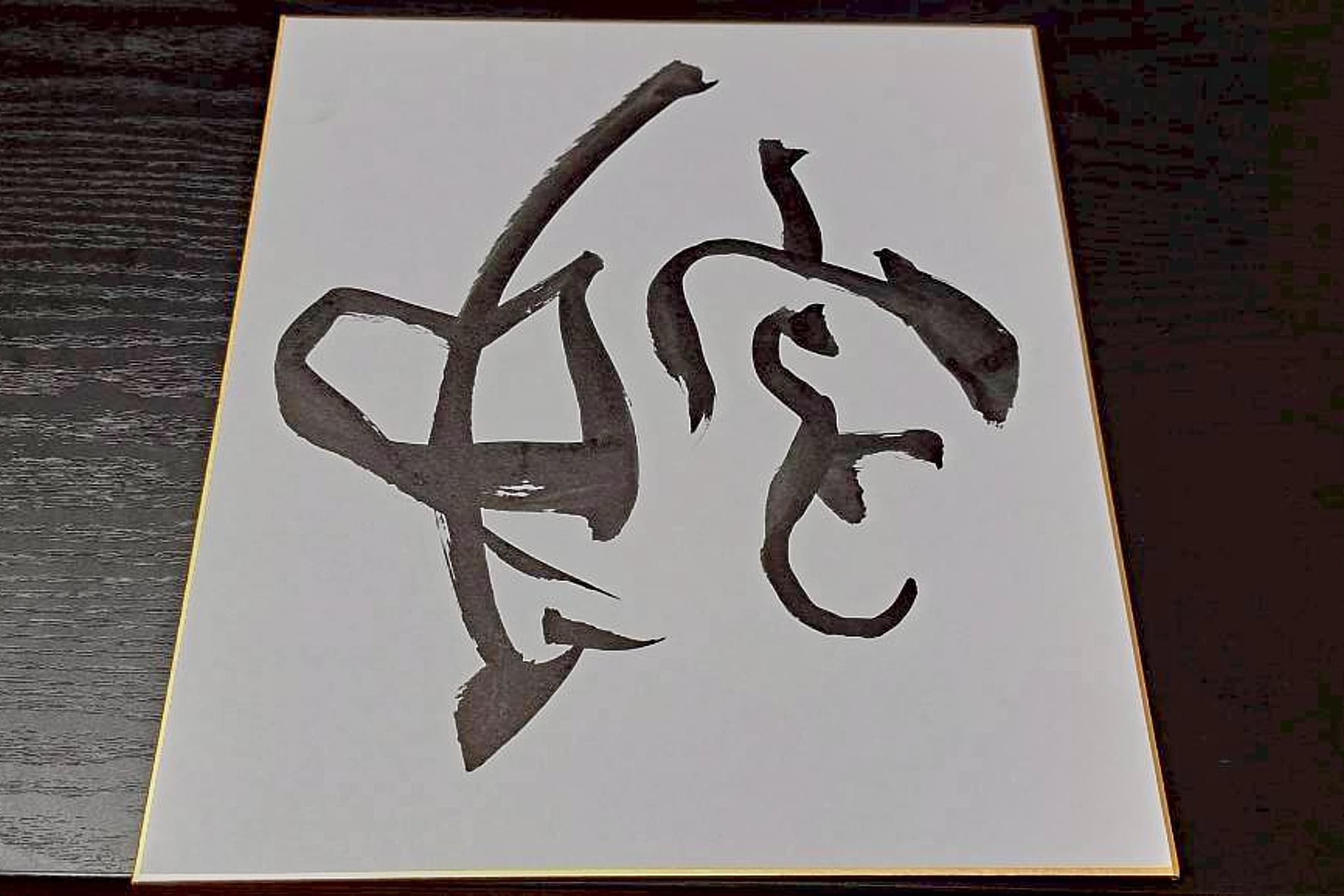 金縁の色紙に墨で記した一字「蛇」