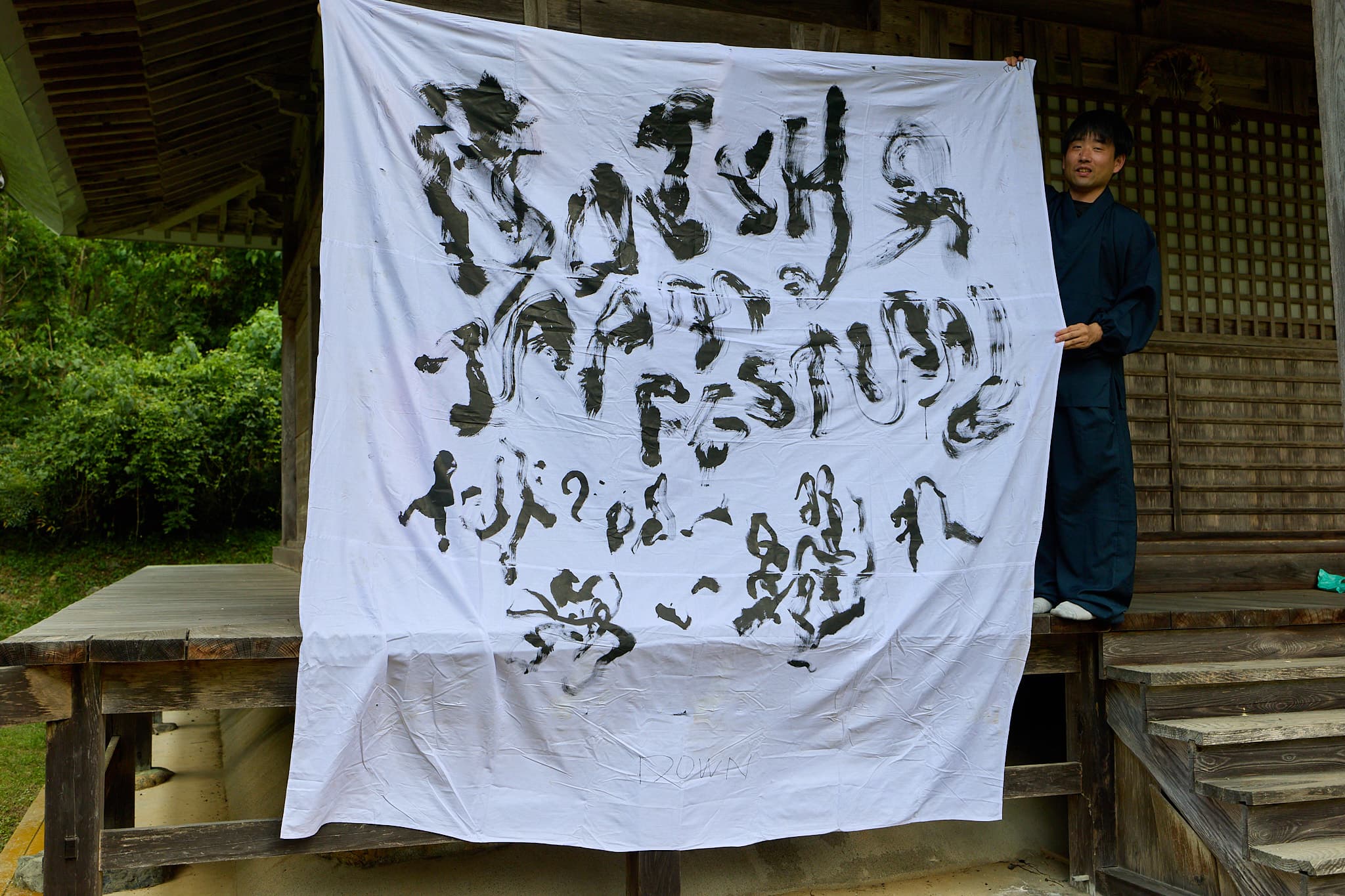 白布に「BATSHO JAPAN FESTIVAL」と墨で大書した大型書道作品を掲げる森下友喜